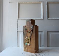 a wooden block with a necklace hanging from it's side on top of a table