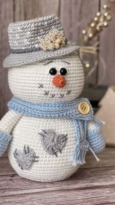 a crocheted snowman sitting on top of a wooden table