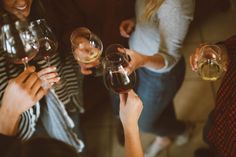 several people holding wine glasses in their hands