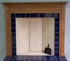 an empty fireplace with blue tiles and a wooden mantle on the wall above it is a black shovel