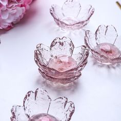 pink glass bowls with flowers in them on a table