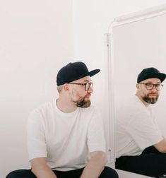 a man sitting in front of a mirror looking at his reflection