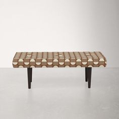 a bench made out of wood and fabric with circles on the back, sitting in front of a white wall