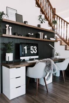 a desk with a computer on top of it next to a stair case and some plants