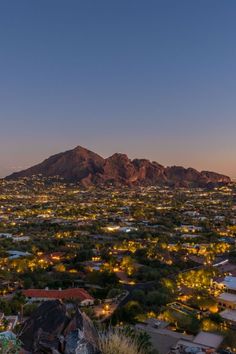 an aerial view of a city with mountains in the background at night, lit up by street lights