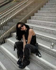 a woman sitting on some stairs with her legs crossed and wearing black boots, sunglasses and knee pads