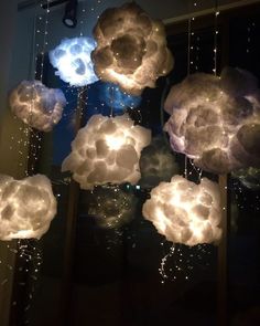 some clouds that are hanging from the ceiling in front of a window with lights on them