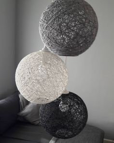 three black and white balls hanging from the ceiling in a living room with grey walls