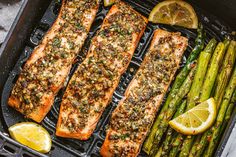 grilled salmon and asparagus on a grill with lemon wedges, garlic bread and seasoning