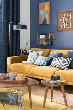 a living room with blue walls and yellow furniture in the center, along with coffee tables