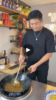 a man cooking food in a wok on top of a stove next to a counter