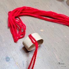 a piece of red string sitting on top of a wooden floor