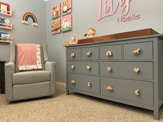 a baby's nursery room with a gray dresser and grey chair