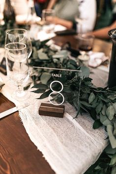 the table is set with place cards and greenery