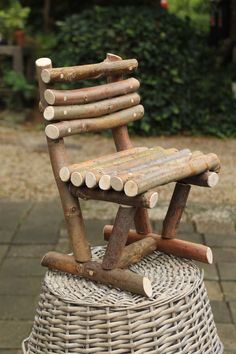 a chair made out of logs sitting on top of a wicker basket