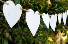 white paper hearts are hanging on a rope