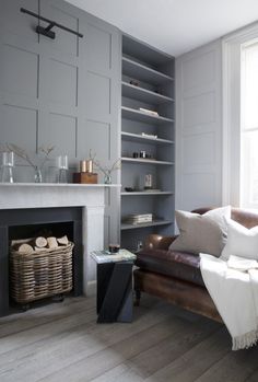 a living room filled with furniture and a fire place in front of a book shelf