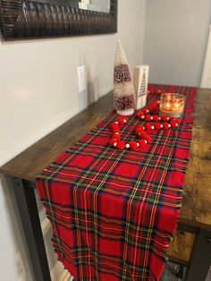 the table is covered with red and black plaid fabric, candles, and candy canes