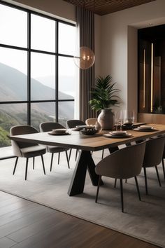 a dining room table with chairs and a vase on the table in front of a large window