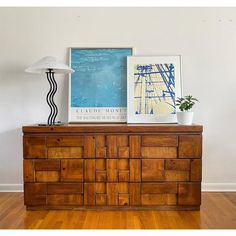 a wooden dresser sitting on top of a hard wood floor next to a white lamp