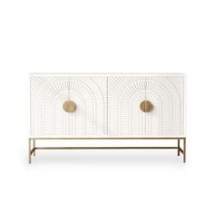 a white and gold cabinet with two brass knobs on the front, and an arched design