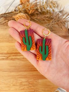 a pair of wooden earrings in the shape of a cactus