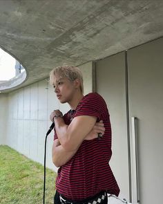 a man standing in front of a building with his arms crossed while holding a microphone