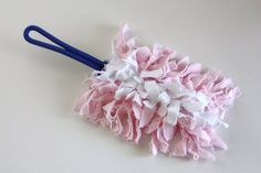 a pink and white flower on a blue handled cleaning brush sitting on top of a table