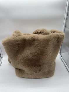 a brown furry purse sitting on top of a white chair next to a wall and window