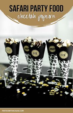 four cones filled with popcorn sitting on top of a black and white table cloth covered in confetti