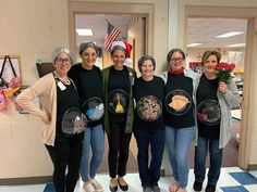 four women holding plates with food on them in front of an american flag and other decorations