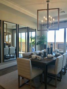 a dining room table with white chairs and a chandelier hanging from the ceiling