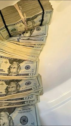 stacks of money sitting on top of each other in front of a white sink with water running down the side