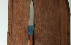 a knife sticking out of the side of a wooden door with blue and orange paint on it