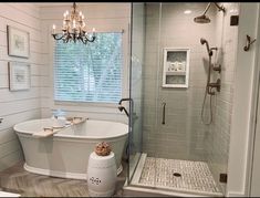 a white bath tub sitting next to a walk in shower under a chandelier