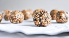 several balls of granola are lined up on a white tablecloth with more in the background