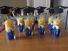 graduation decorations made out of cereal in vases on a table with hats and tassels