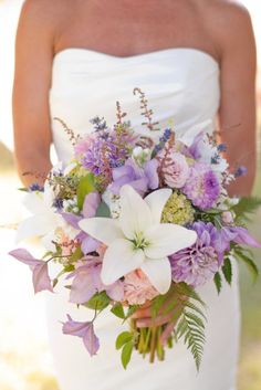 a bride holding a purple and white bouquet