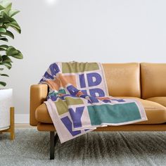 a couch with a blanket on it in front of a potted plant