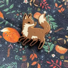 a brown and white fox pin sitting on top of a blue fabric