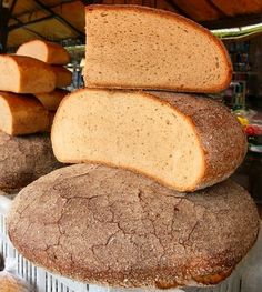 a pile of bread sitting on top of each other in front of a basket filled with sliced bread