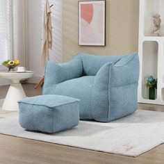 a blue chair and footstool in a living room with white rugs on the floor