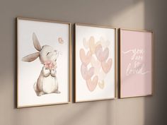 three framed art prints on the wall in a child's room with pink accents