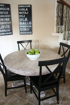 a bowl of fruit sitting on top of a wooden table next to a stair case