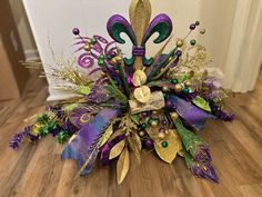 a purple, green and gold flower arrangement sitting on top of a hard wood floor