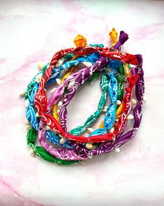 the colorful bracelets are tied together on the pink marble counter top with beads and pearls