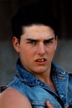 a young man wearing a denim shirt and looking at the camera with an angry look on his face