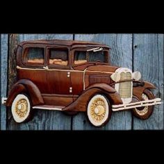 an old model t car hanging on the side of a wooden fence with wood planks