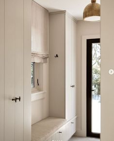 an empty room with white cupboards and a black door in the center is lit by a light fixture