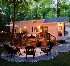 two people sitting on lawn chairs in front of a small house with deck and patio lighting